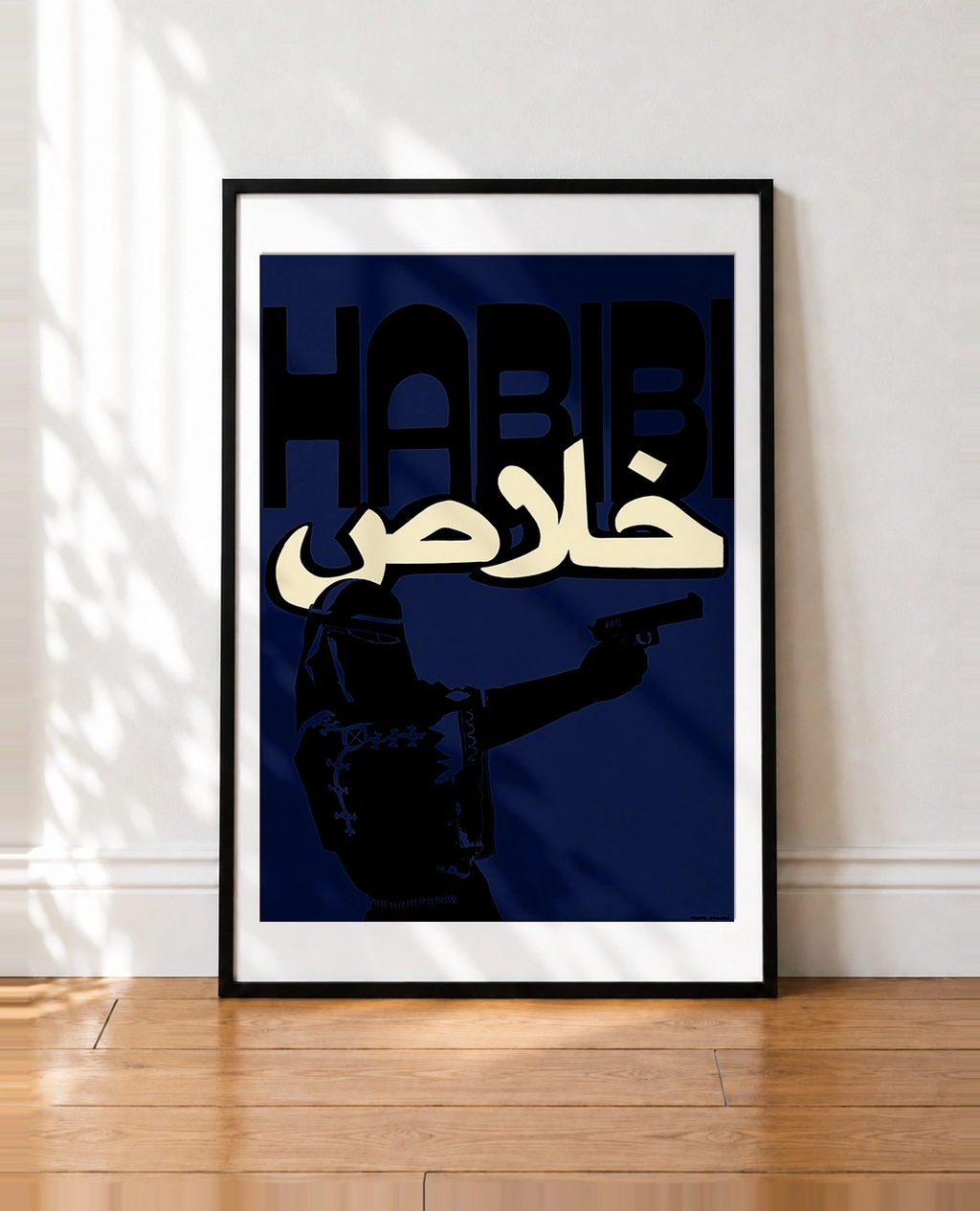 Framed Habibi Khalas Blue poster: veiled figure holding a gun under bold HABIBI and Arabic lettering on a deep blue background, leaning against a white wall
