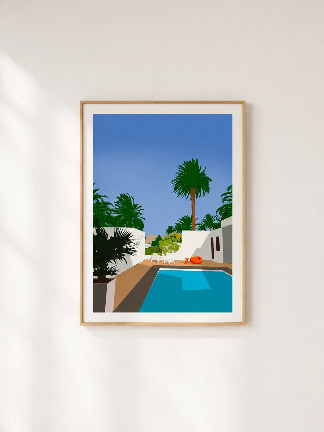 Wooden framed print of a pool surrounded by palm trees and white Mediterranean architecture
