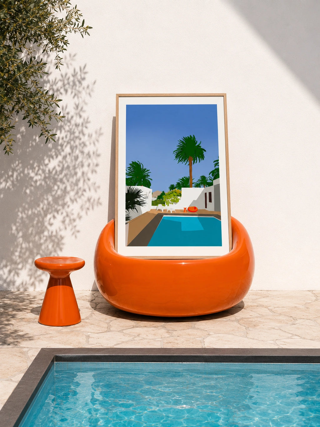 César Manrique House framed poster resting in an orange poolside chair next to a real swimming pool
