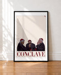 framed Minimalist illustration of three cardinals in purple cassocks smoking cigarettes against a cream background, with the title Conclave in burgundy letters
