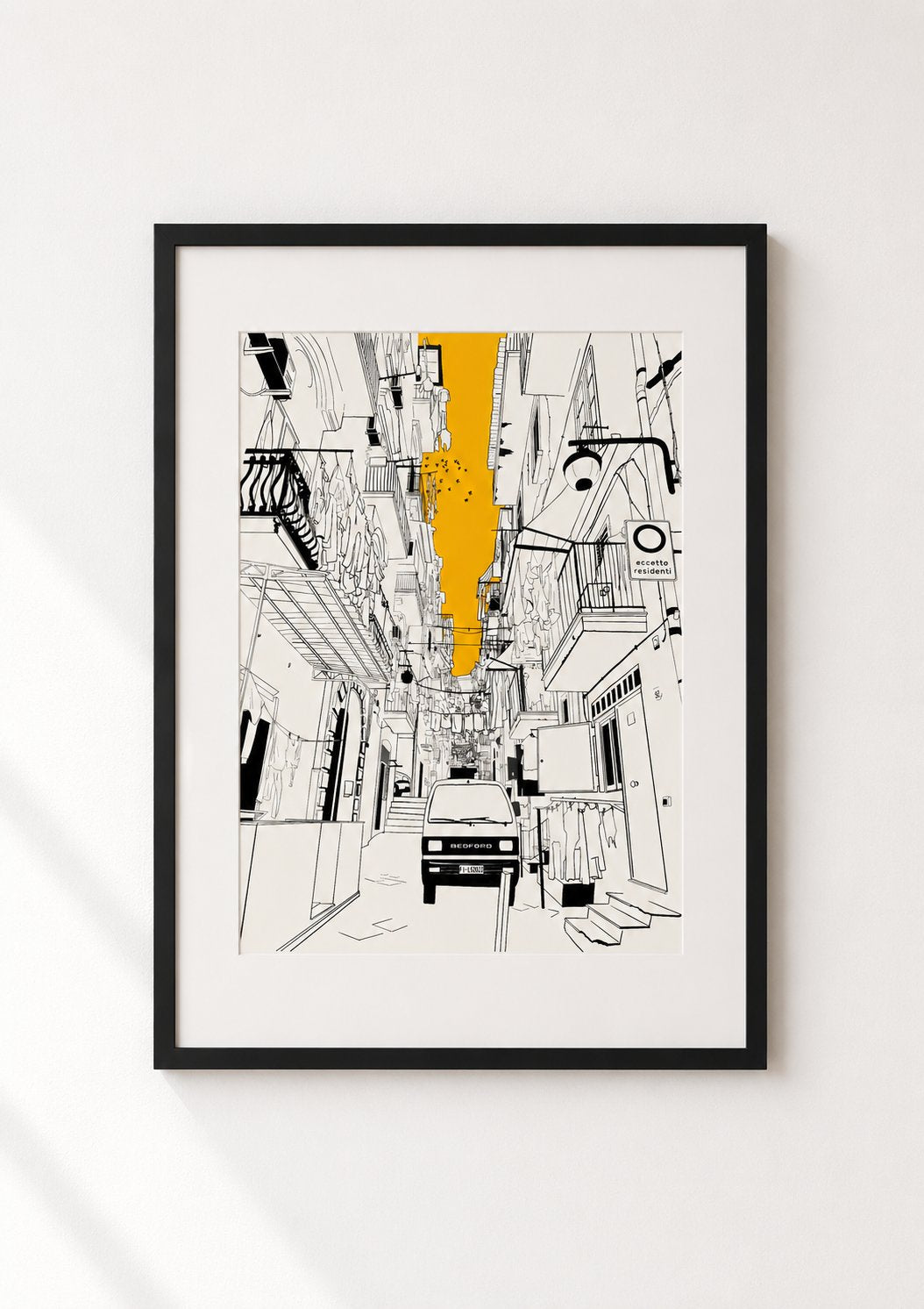 Black framed print of a Naples alleyway illustration with hanging laundry and a vintage van, displayed on a white wall
