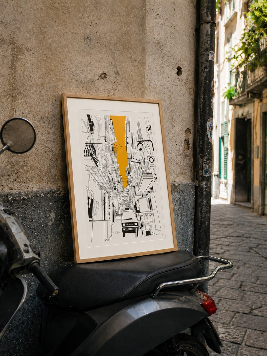 Framed Naples alleyway print leaning against a wall on a parked scooter in an Italian street
