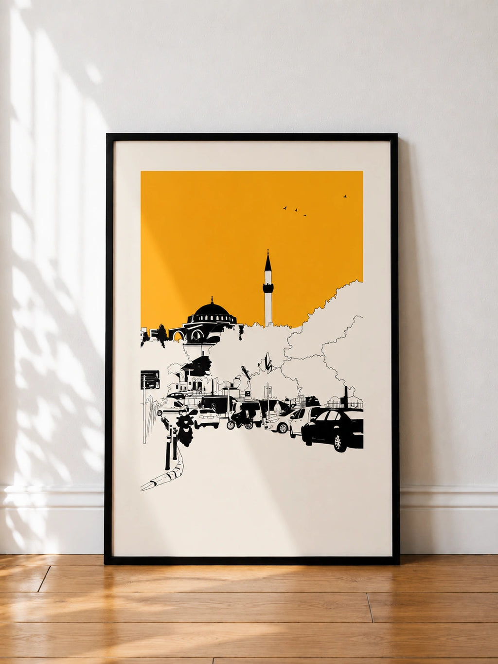 Black framed Istanbul mosque and minaret print with an orange sky leaning against a wall
