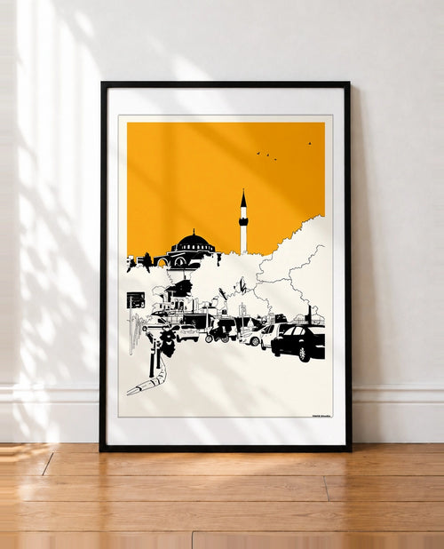 Black framed Istanbul mosque and minaret print with an orange sky leaning against a wall
