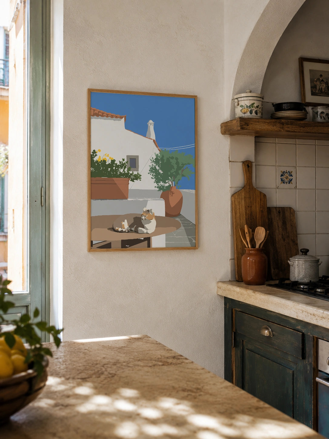 Mediterranean cat framed poster hanging in a rustic kitchen with tiled backsplash and lemons
