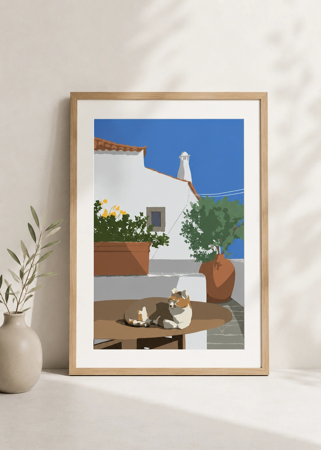 Mediterranean cat poster hanging on a wall with an archway view of the sea and an olive tree
