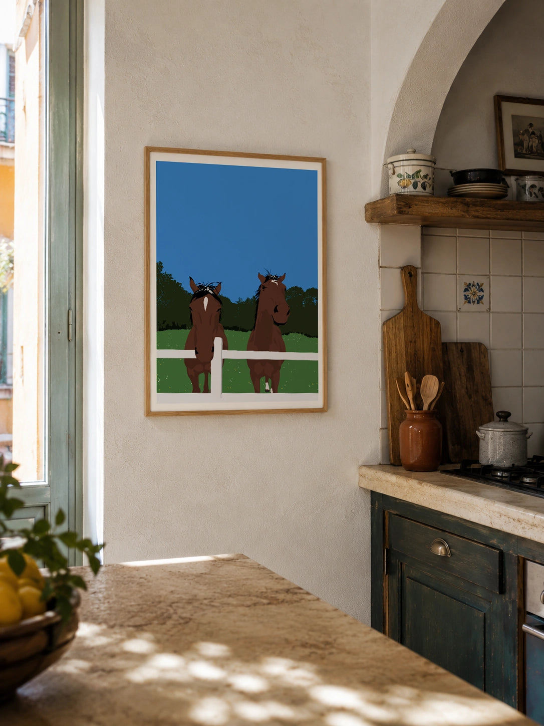 Two horses framed poster hanging in a rustic kitchen with tiled backsplash and lemons
