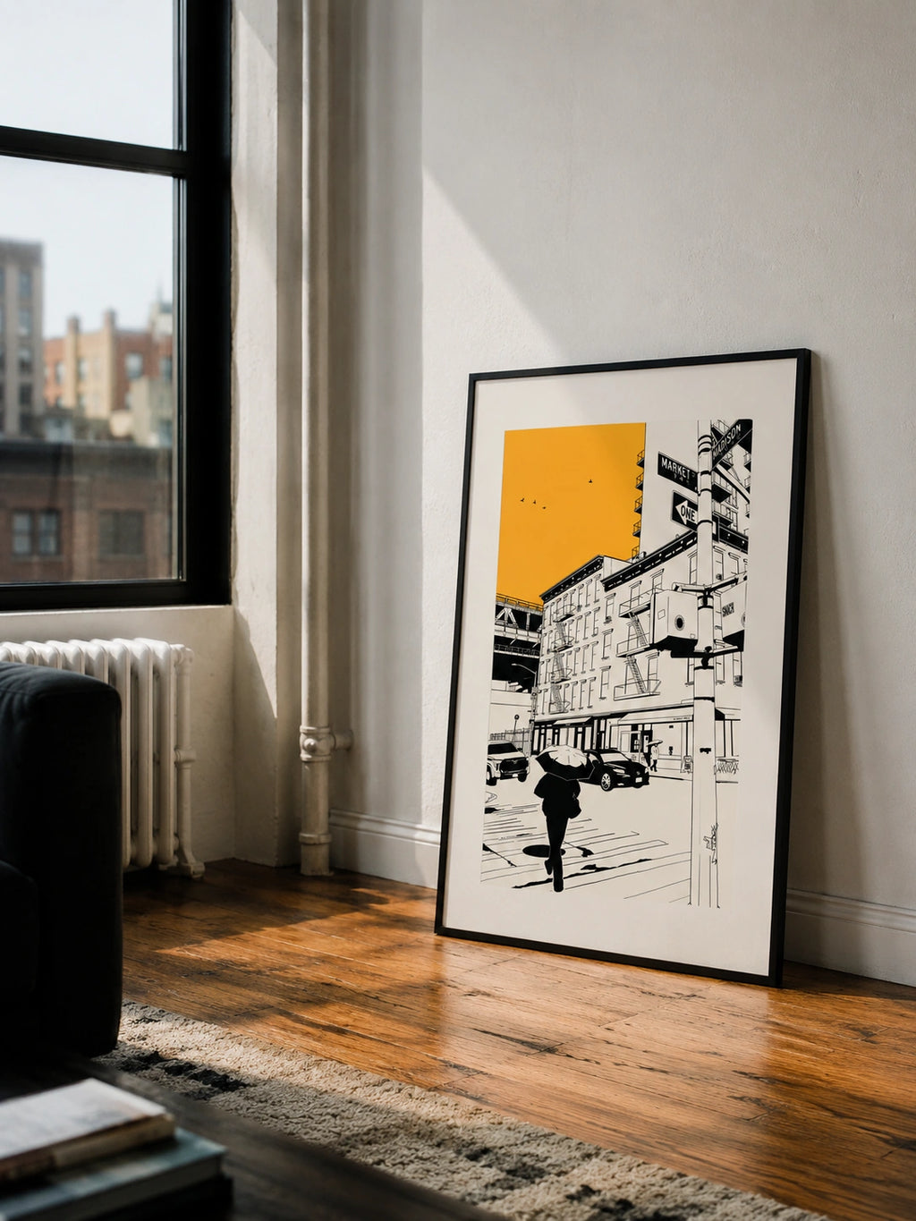 Framed New York City street poster leaning against a wall near a window in a loft apartment
