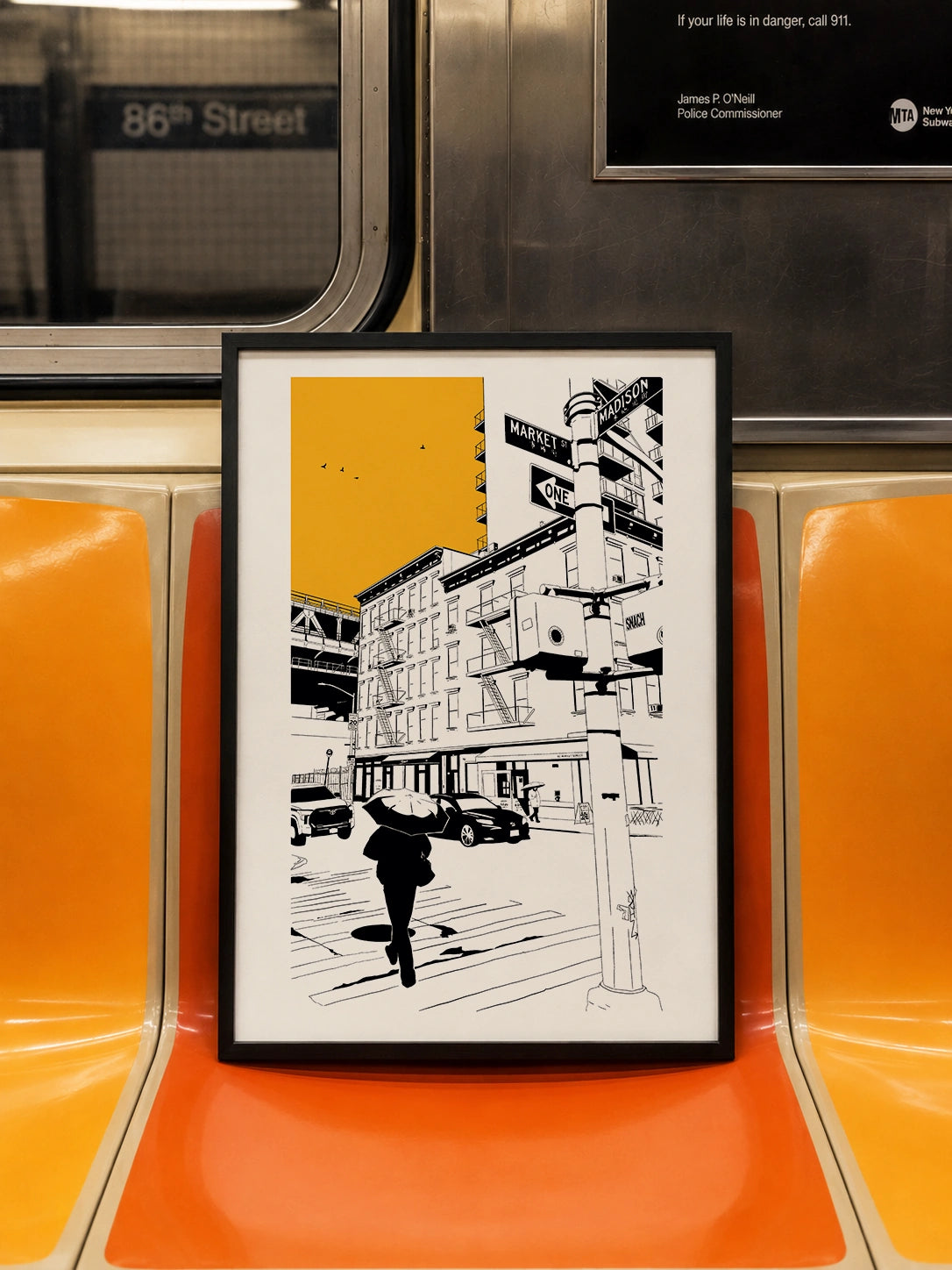 Framed New York City street print displayed on an orange subway seat with 86th Street sign visible
