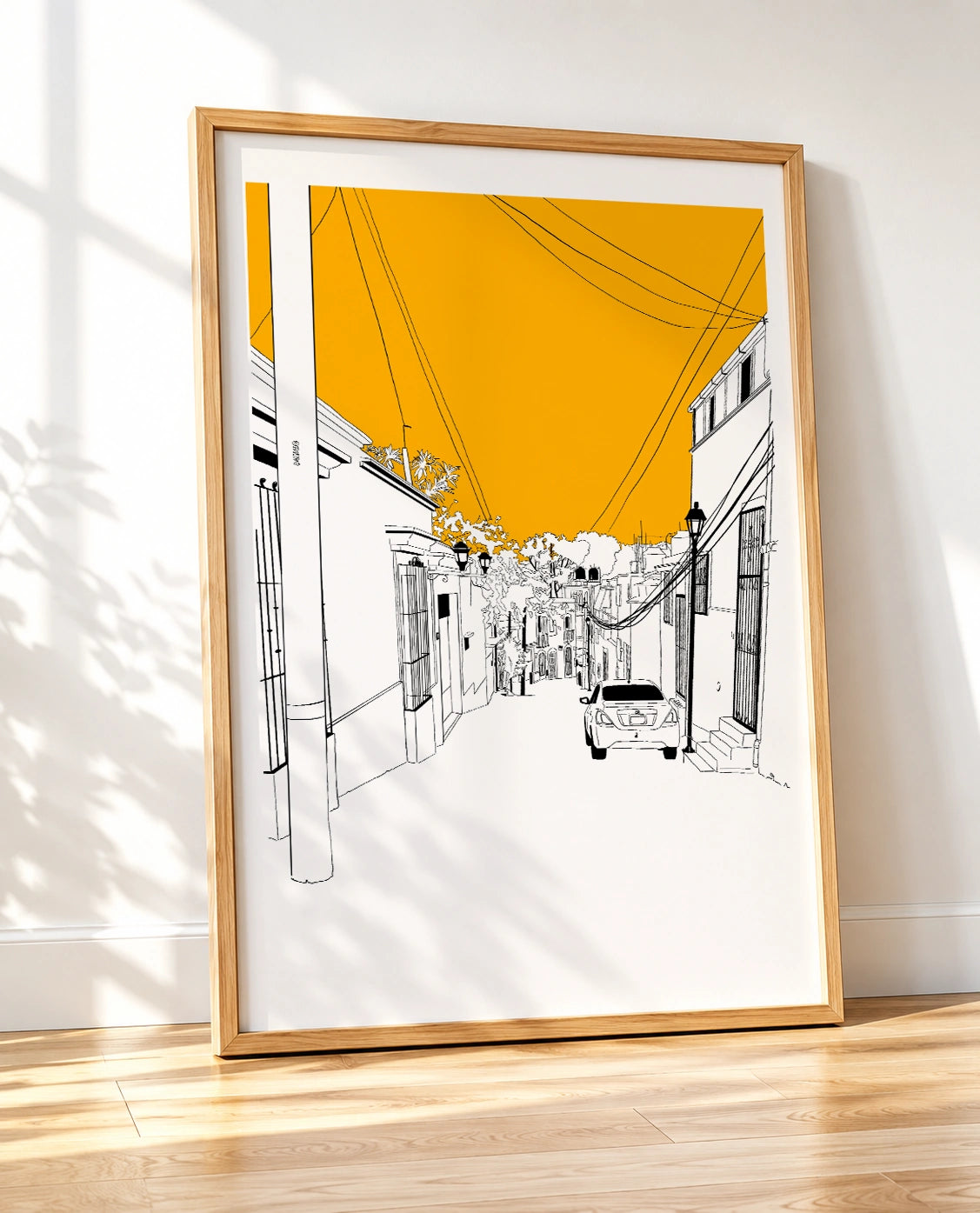 Wooden framed print of an Oaxaca street with an orange sky, power lines, and a parked car, shown at an angle
