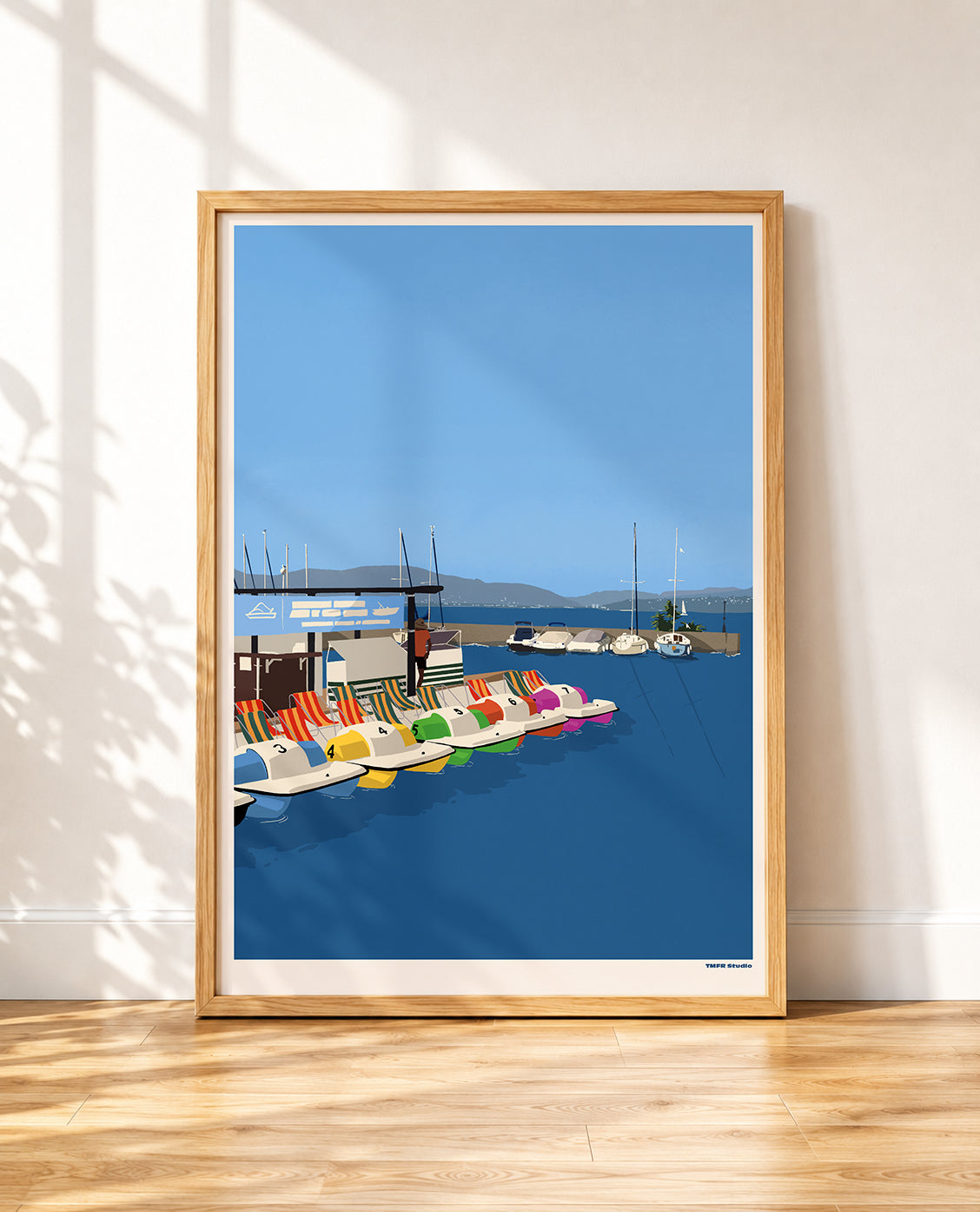 framed print of colorful pedal boats docked on a lake with sailboats and mountains