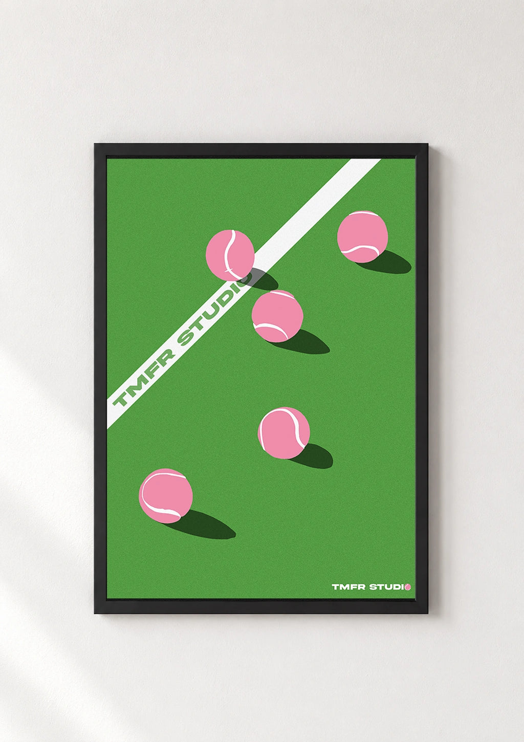Black framed pink tennis balls poster on a green court background
