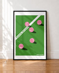 A framed minimalist tennis-themed art print leaning against a white wall on a wooden floor. The print features a green court background with pink tennis balls, a white diagonal boundary line, and the text 'TMFR STUDIO' in green and white, enclosed in a black frame.
