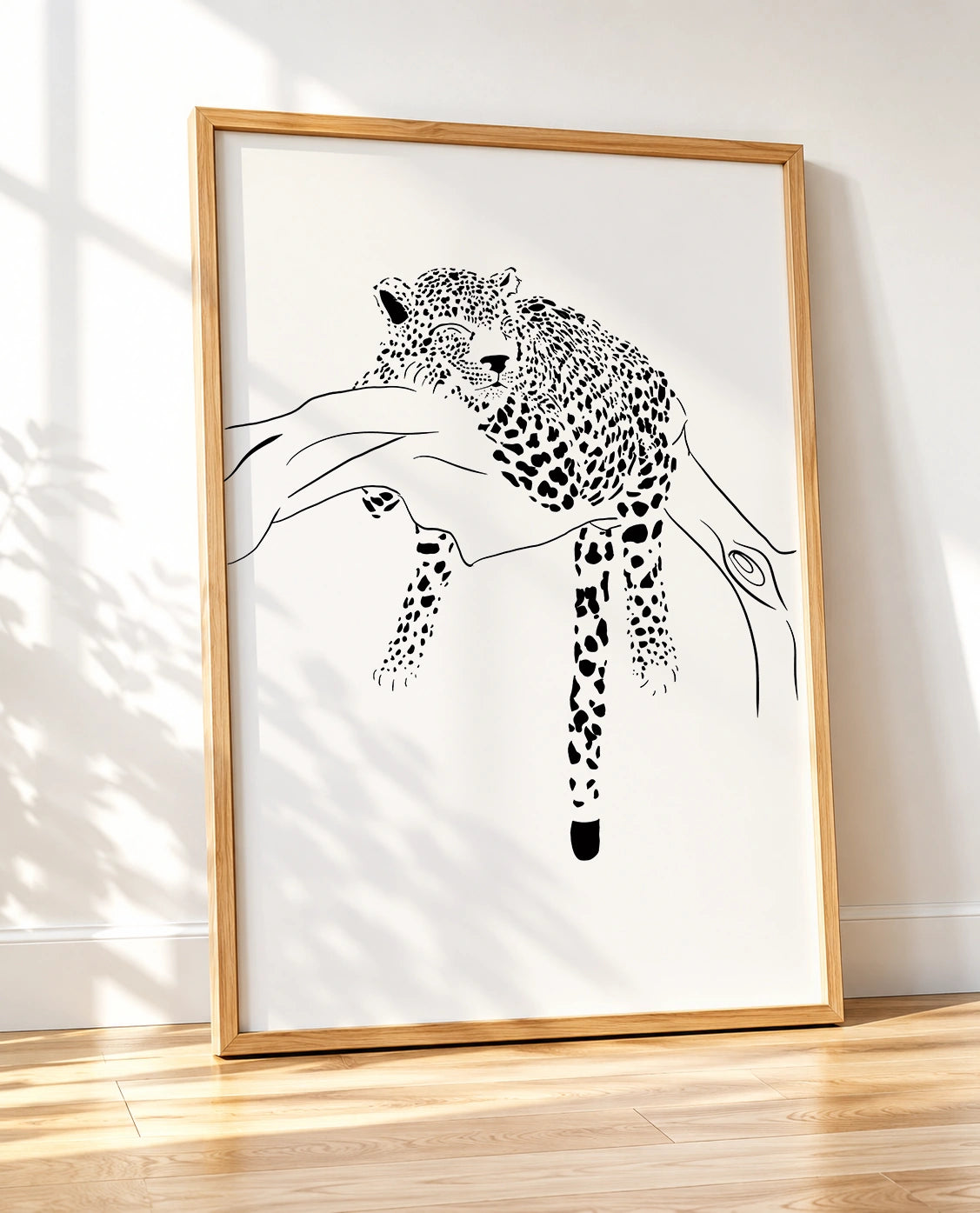 Wooden framed black and white print of a leopard sleeping on a tree branch, shown at an angle
