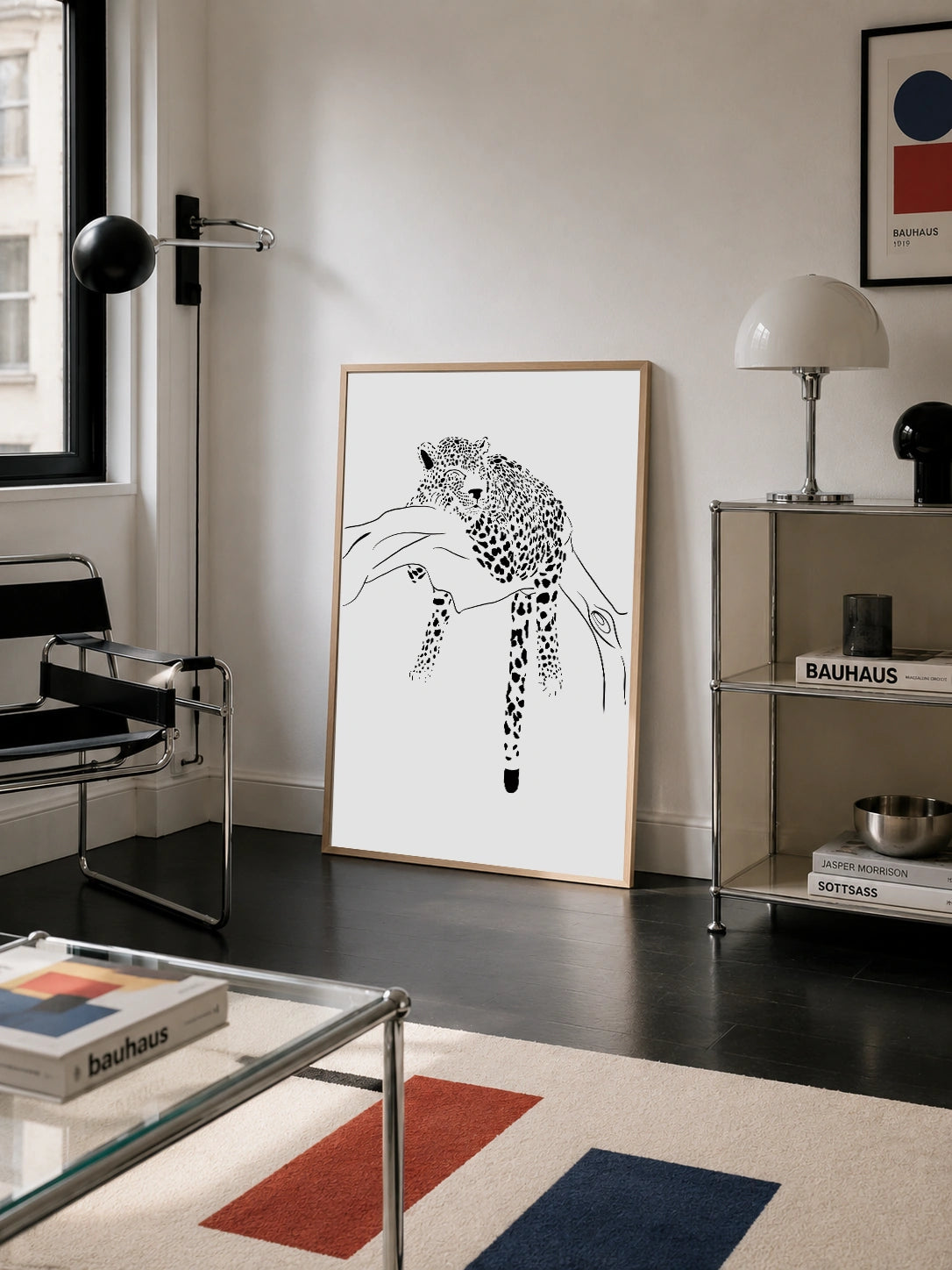 Sleeping Leopard framed poster leaning against a wall in a Bauhaus style living room with a colorblock rug
