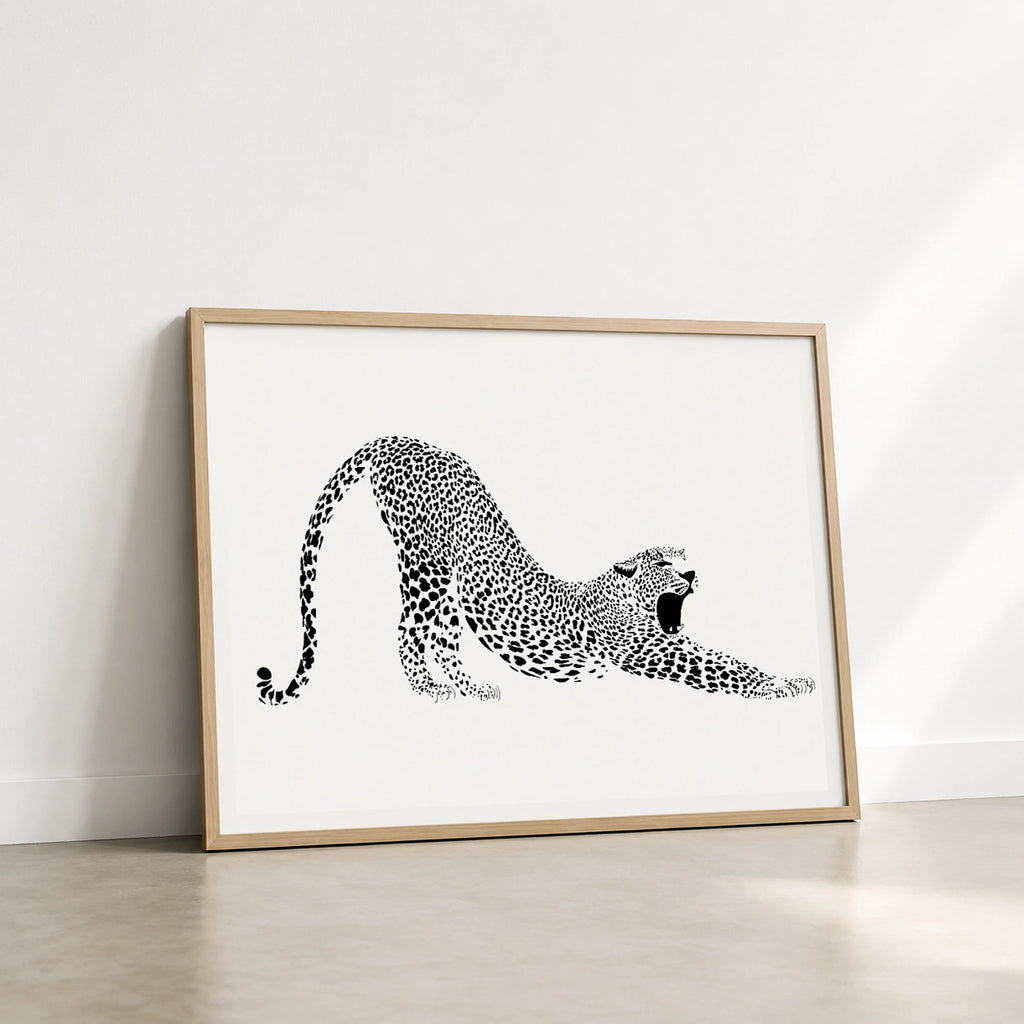 Wooden framed black and white print of a leopard stretching and yawning on a white background
