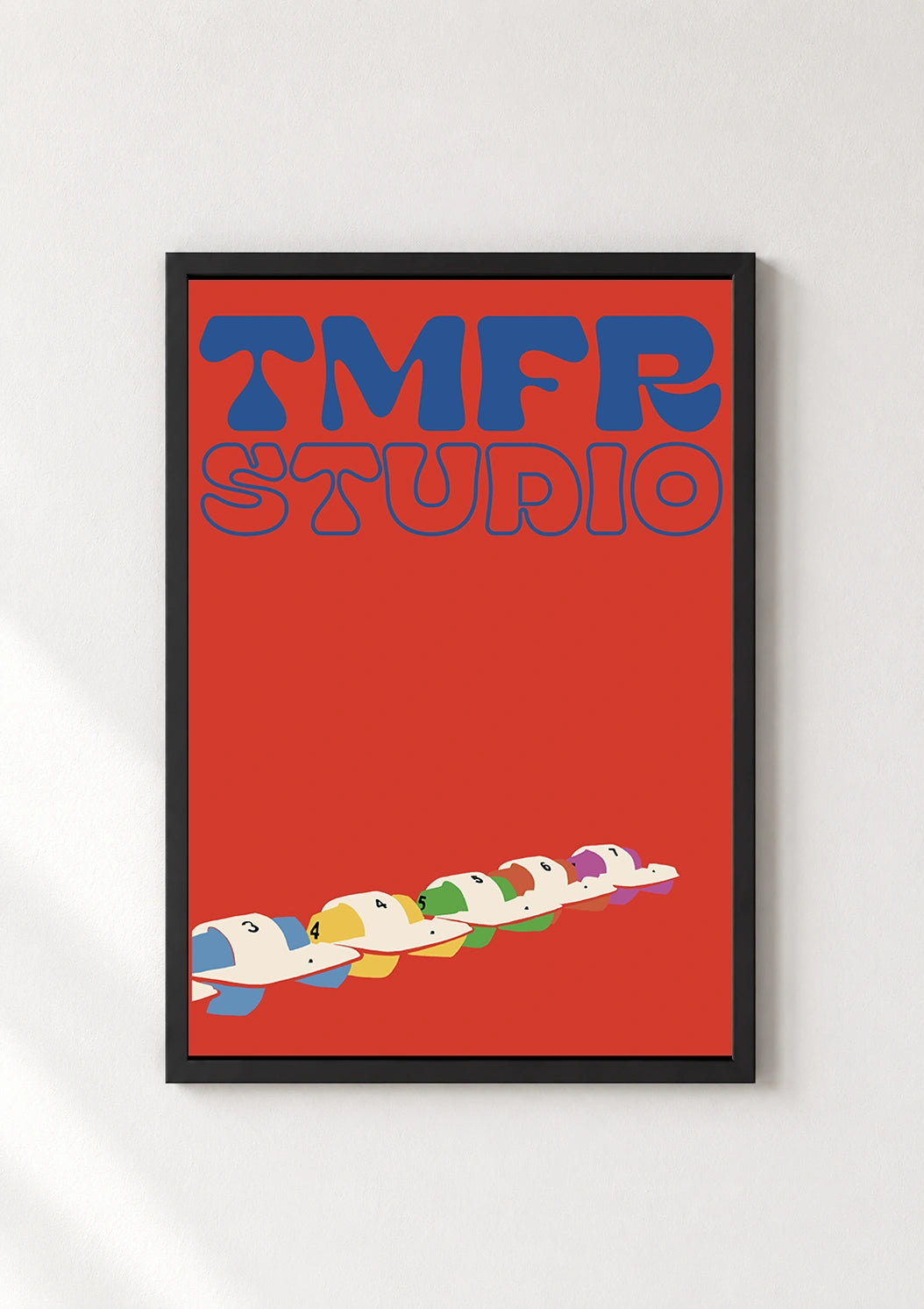 TMFR Studio poster in a thin black frame displayed against a plain white wall
